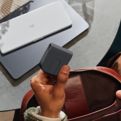 Logitech Mobi Fold mouse Graphite folded in the hand next to a bag