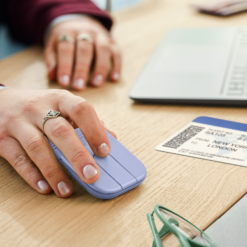 Logitech Mobi Fold mouse Lilac in use on a desk beside a laptop