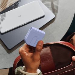 Logitech Mobi Fold mouse Lilac folded in the hand next to a bag